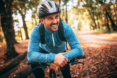 Cosmetic dental implants | man smiling on bicycle