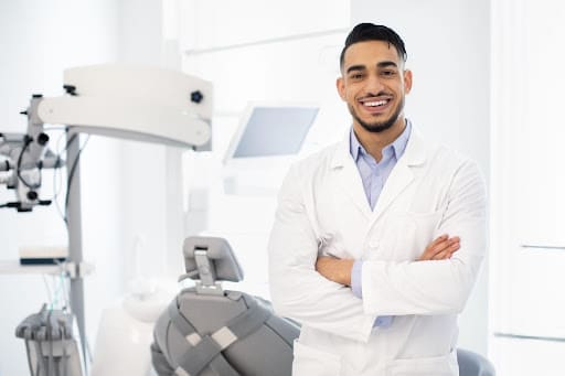 Dentist posing in front of the dental chair with a radiant smile.
