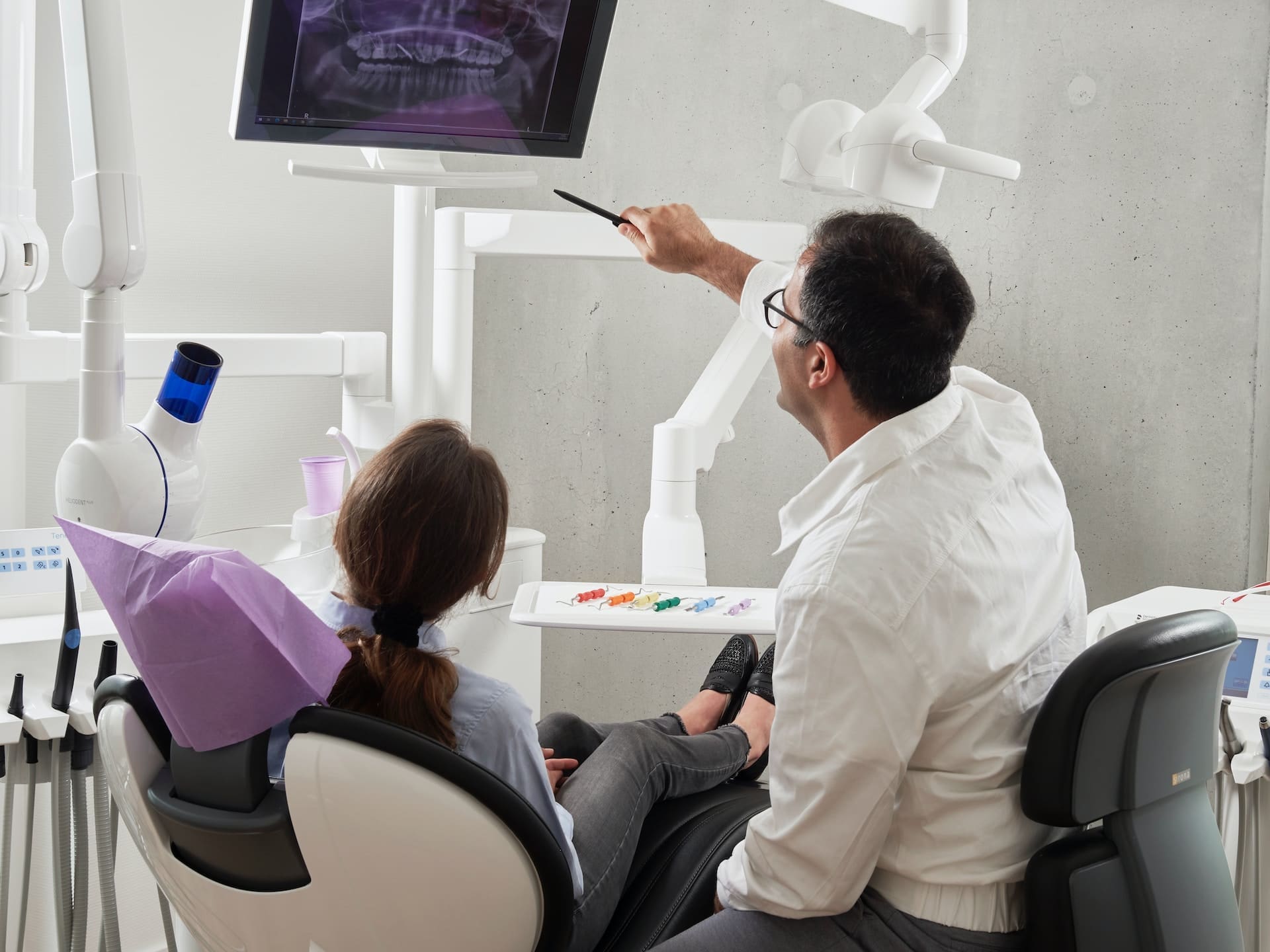 Dentist displaying treatment results to patient on medical monitor.