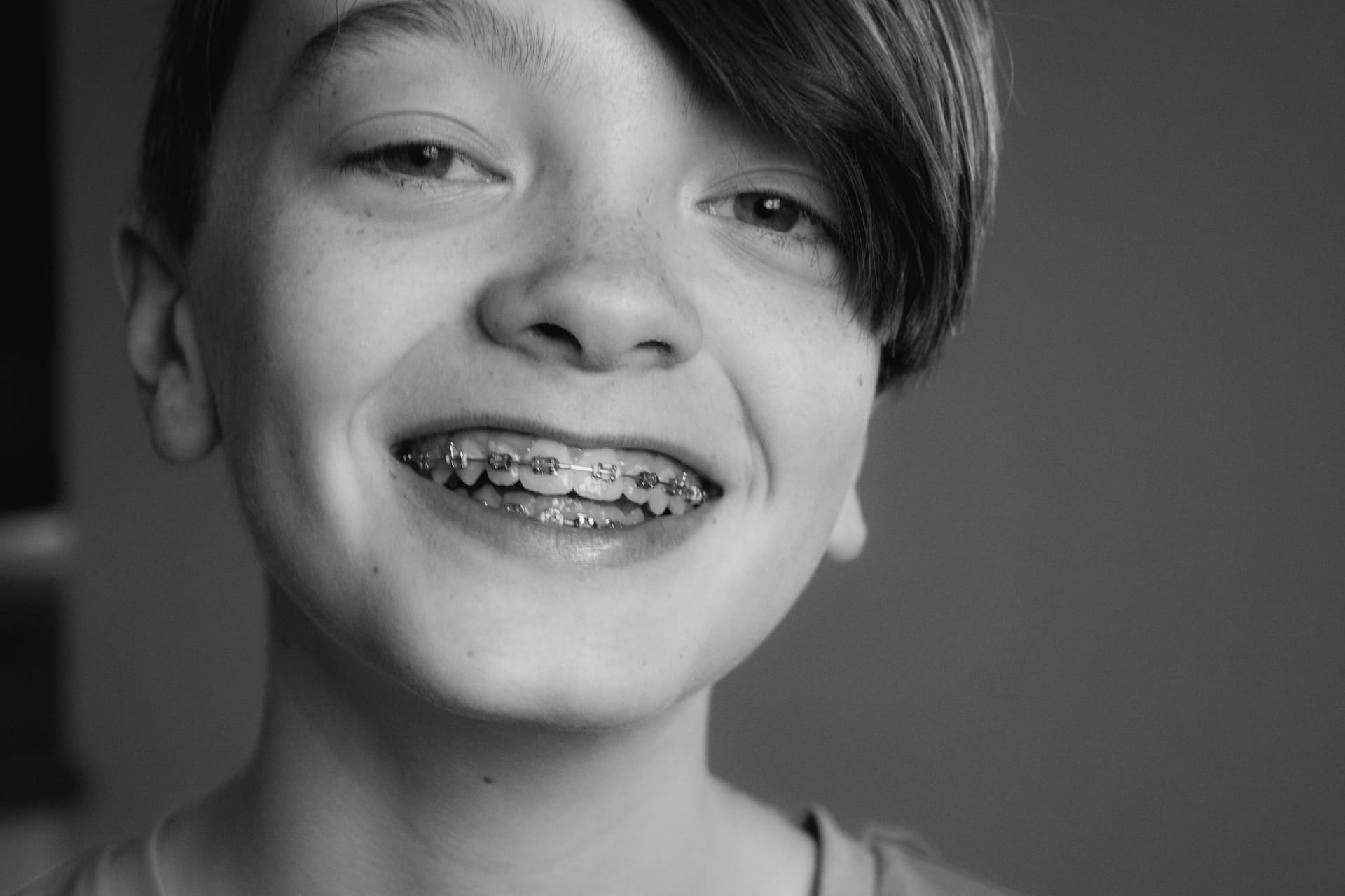 Teenage girl smiling while displaying braces on her teeth, expressing satisfaction.