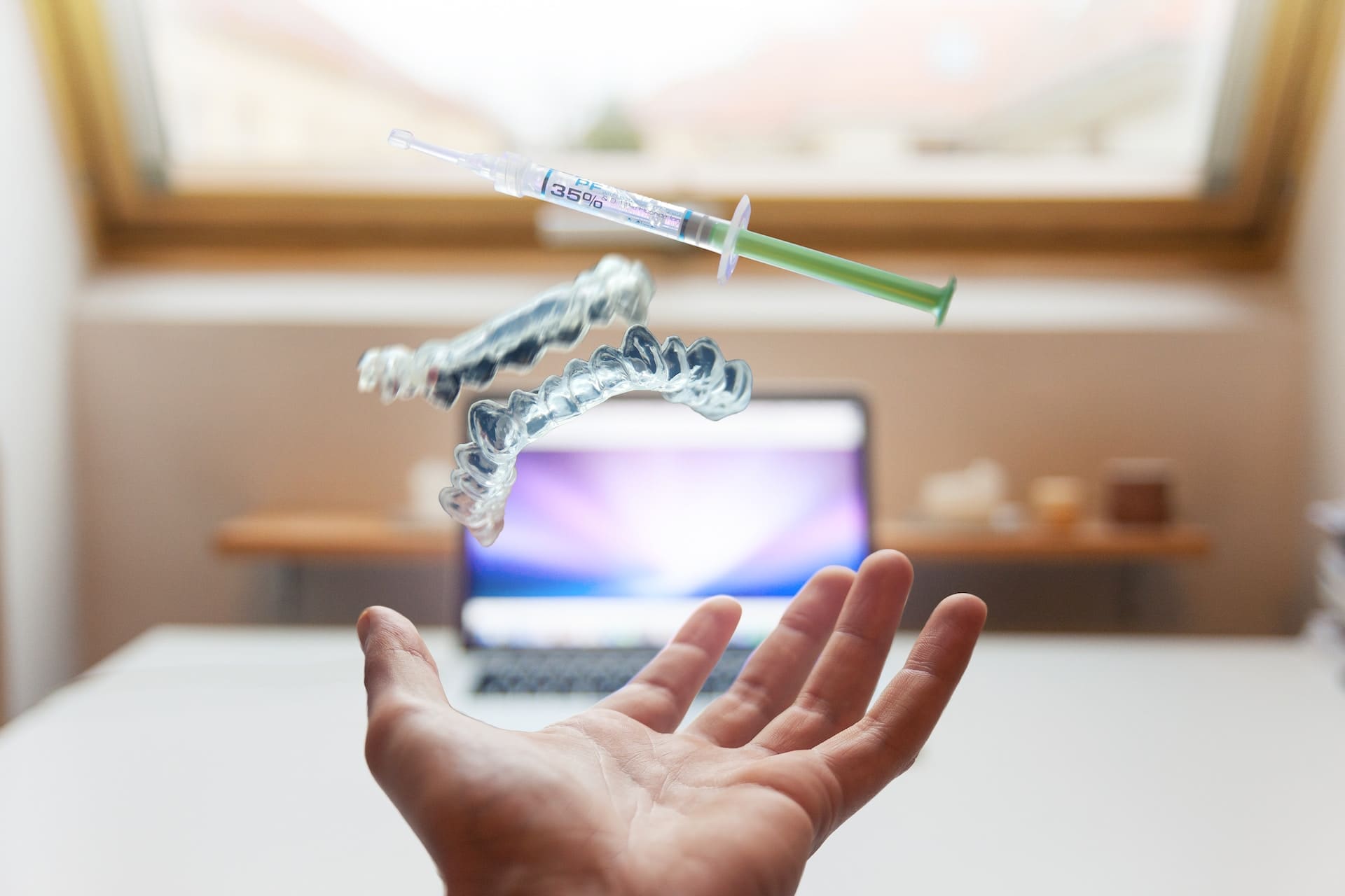 Hand holding a syringe with Invisalign aligners in the air against an ecstatic background.